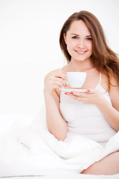 Woman sitting on bed with cup — Stock Photo, Image