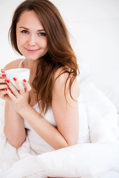 Portrait de femme au lit tenant une tasse — Photo