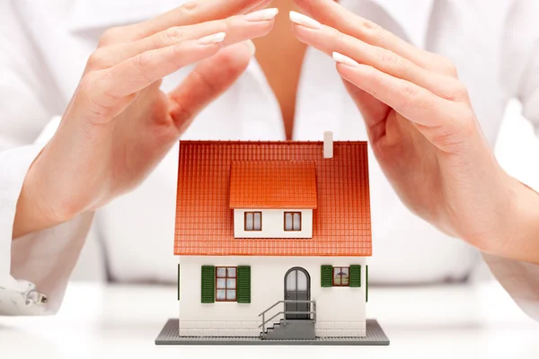 Female hands saving small house with a roof — Stock Photo, Image