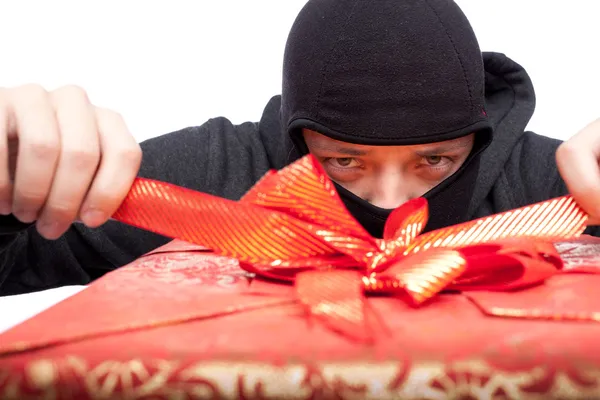 Räuber hält verpacktes Weihnachtsgeschenk in der Hand — Stockfoto