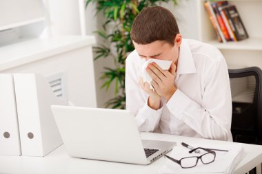 Man sneezing while working clipart