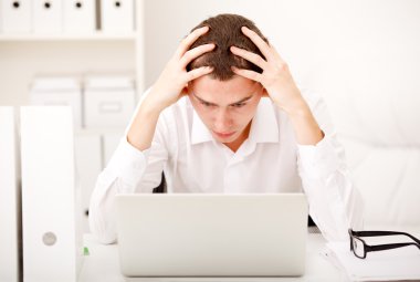 Despairing businessman sitting at desk clipart