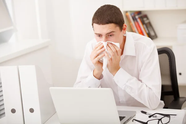 Man sneezing while working — Stock Photo, Image