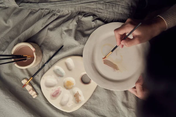 Female artisan smearing paint on plate — Stock Photo, Image