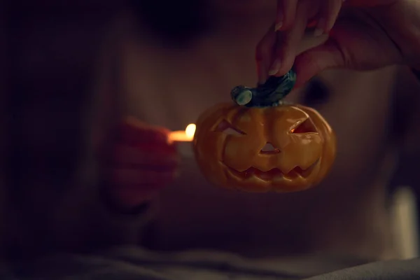 Femme méconnaissable mettant la bougie dans le titulaire d'Halloween — Photo