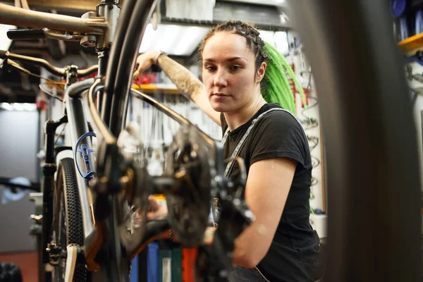 Female mechanic checking bicycle in garage — Stock Photo, Image