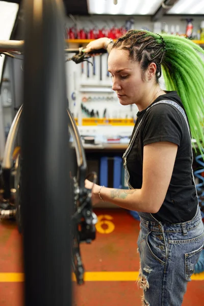 Kvinnlig mekaniker undersöker trasiga cykel — Stockfoto