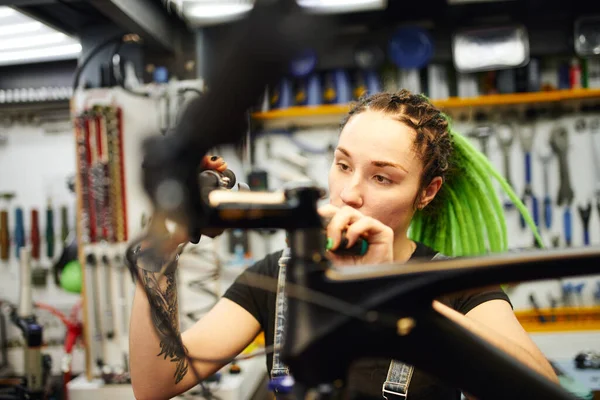 Odaklanmış kadın bisiklet gidonunu tamir ediyor — Stok fotoğraf