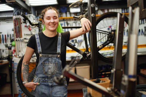 Bisiklet tamirhanesinde gülümseyen olumlu kadın. — Stok fotoğraf
