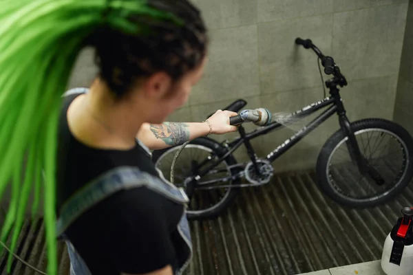 Woman washing bike in workshop