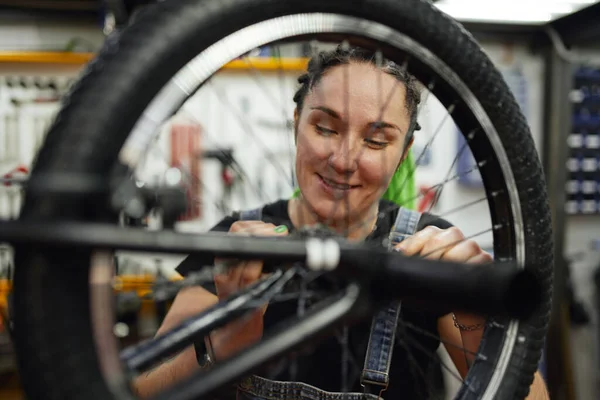 Gelukkig vrouw repareren fiets in garage — Stockfoto