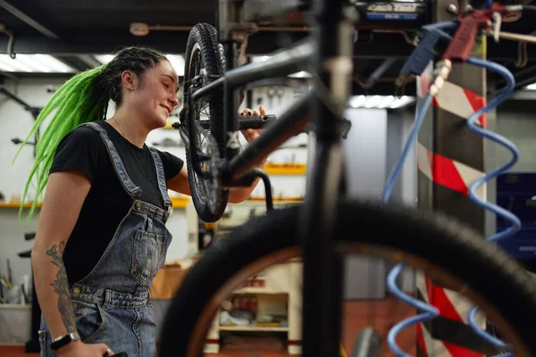 Cheerful mechanic repairing bicycle in workshop — Stock Photo, Image