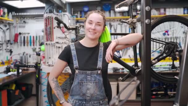 Позитивная женщина-механик рядом со сломанным велосипедом — стоковое видео