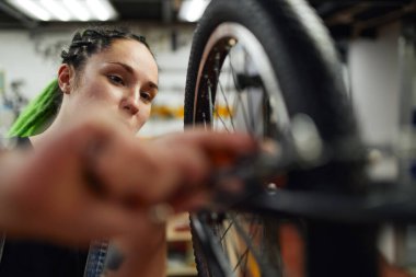 Sakin kadın usta atölyede bisiklet tekerleğini tamir ediyor.