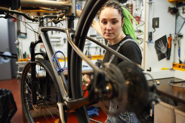 Kvinnlig mekaniker reparera cykel i verkstad — Stockfoto