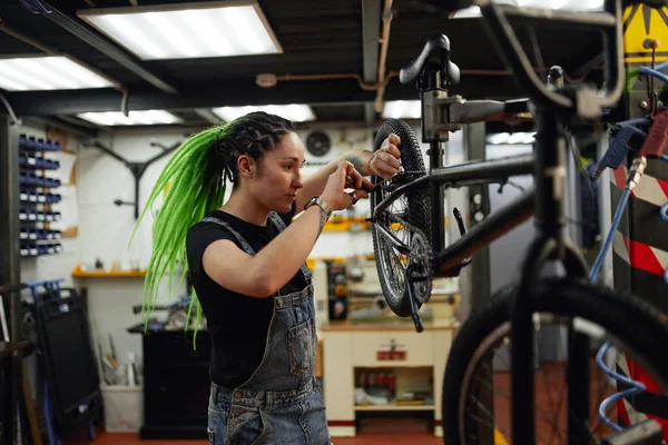 Kadın tamirci atölyede bisiklet tamir ediyor. — Stok fotoğraf