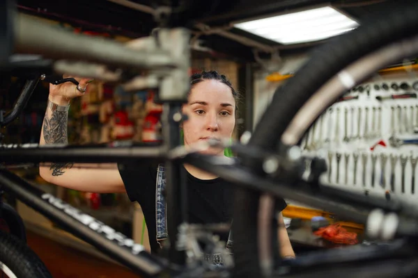 Atölyede bisiklet tamir eden odaklanmış bir kadın. — Stok fotoğraf