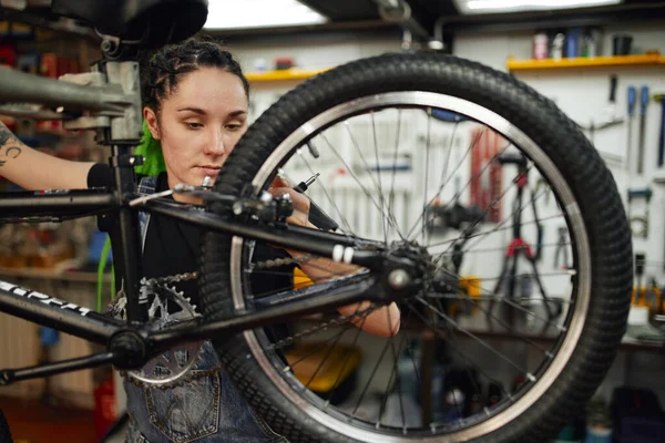 Mecánica femenina con llave inglesa reparando bicicleta en taller — Foto de Stock