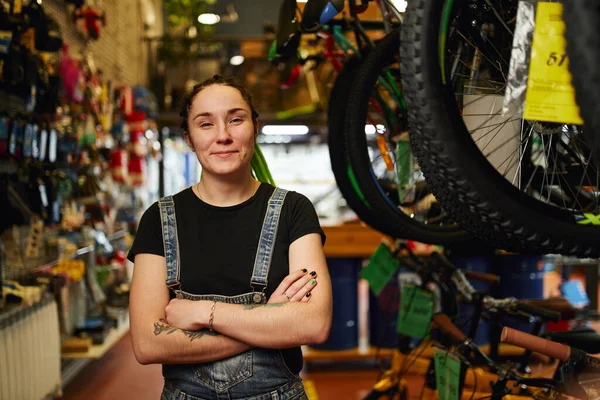 Bisiklet dükkanında kollarını kavuşturmuş gülümseyen kadın. — Stok fotoğraf