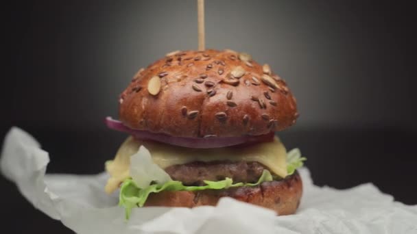 Handgemaakte hamburger draait op verfrommeld papier — Stockvideo