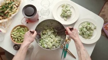 Öğlen yemeğinde tabağa salata koyan isimsiz bir adam.