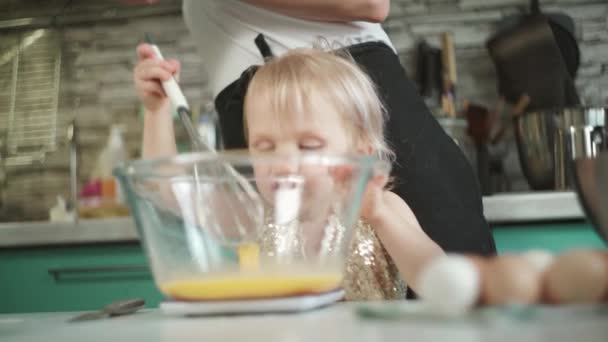 Sevimli çocuk mutfakta annesinin yanında yumurta çırpıyor. — Stok video