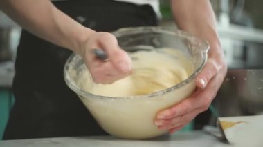 Kırpılmış yüzsüz kadın kremayla çırpıcıyı karıştırıyor