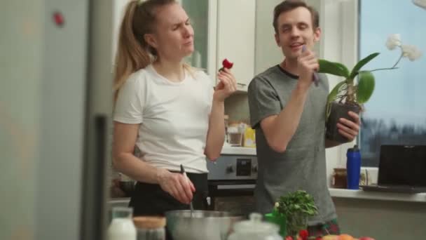 Jóvenes cónyuges positivos cantando mientras preparan la comida juntos en la cocina — Vídeo de stock