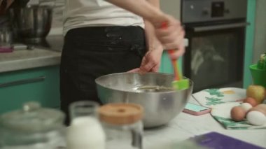 Kırpılmış kadın mutfakta kasede hamur malzemelerini karıştırıyor.