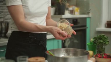 Ekin ev hanımı çiğ hamur ile badem gevreği ekliyor.