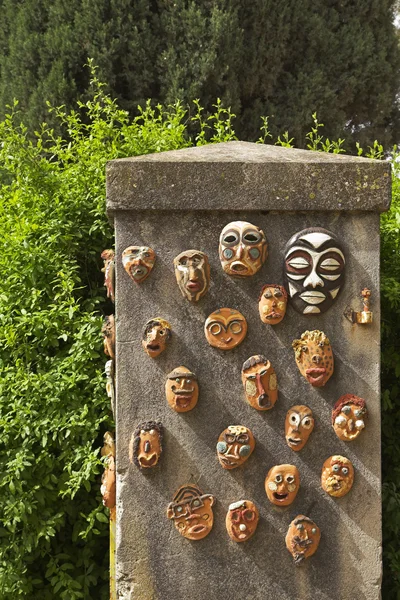 A lápide em um jardim, máscaras rituais cerâmicas decoradas — Fotografia de Stock