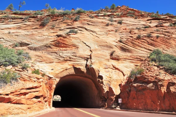 The road passes through a tunnel in the sandstone hill — Stock Photo, Image