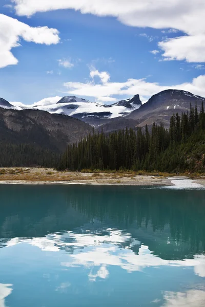 Tyst sjö med kallt vatten, omgiven av snö berg — Stockfoto