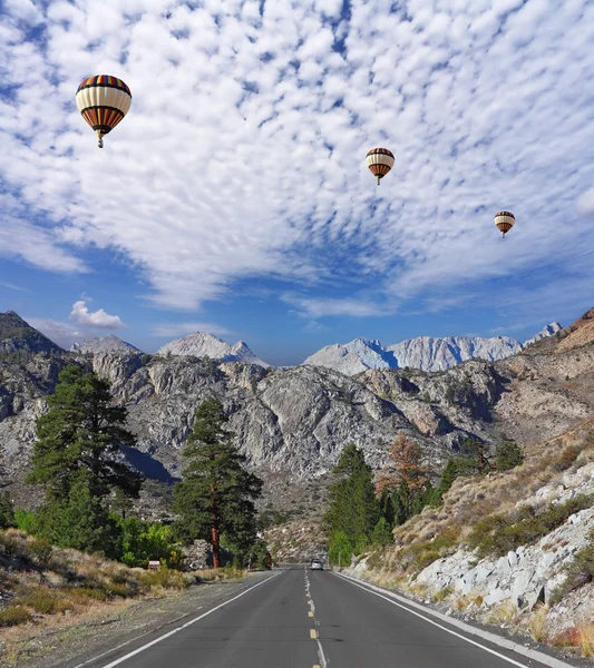 Huge balloons with the basket flying over the road — Stock Photo, Image