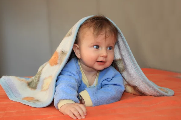 Das blonde Baby, bedeckt mit einer Decke — Stockfoto