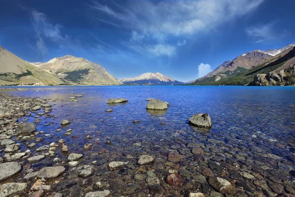 明亮的蓝色水和多岩石的海岸 — 图库照片