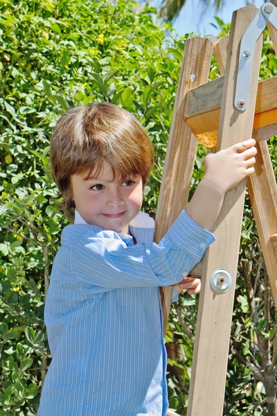Мальчик с улыбкой позирует на стремянке — стоковое фото