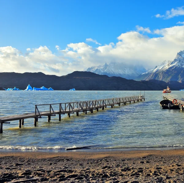 Red tourist ship sails to pier. Gray lake — Stock Photo, Image