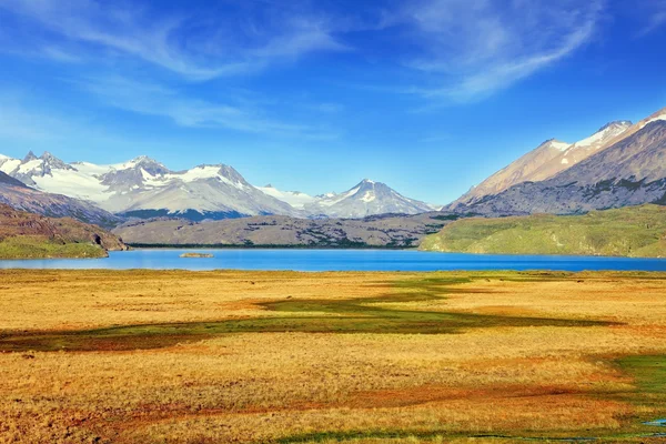 O lago azul no vale cercado por montanhas cobertas de neve . — Fotografia de Stock