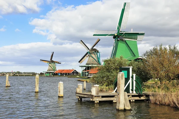 Tres molinos de viento y columnas de atraque en la orilla del canal —  Fotos de Stock