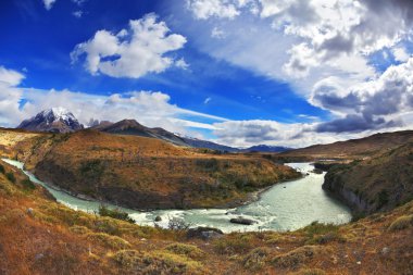 nehre at nalı uçan bulutların altında eğiliyor.