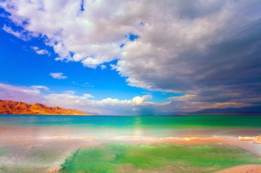  İsrail, efsanevi Ölü Deniz. Alçak kış bulutları yeşil suya yansıyor. Tuzlu denizin pürüzsüz yüzeyi gökyüzünü ve bulutları yansıtır..