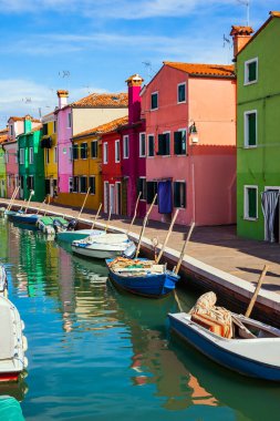 Rengarenk parlak evler kanallara yansıyor. Venedik yakınlarındaki Burano adası. Tekneler kanalların kıyıları boyunca park halindedir. Kültür ve fotoğraf turizmi kavramı