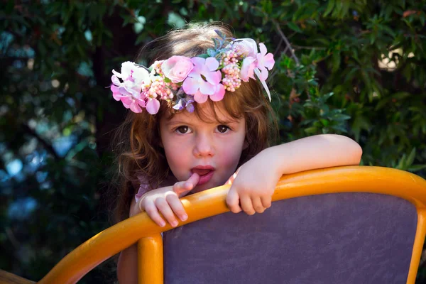 快乐童年的概念 迷人的卷曲的小女孩 头戴花环 躺在夏日花园的椅子上 — 图库照片