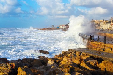 Büyük taşlar sahili büyük fırtına dalgalarından korur. Güçlü kış sörfü kar beyazı köpükle kalkıyor. Tel Aviv 'de toprak seti. Gün batımı. Akdeniz 'de rüzgarlı ve güneşli bir gün. İsrail.