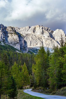 Doğu Alpler 'deki muhteşem dağ silsilesi Dolomitler. Geniş otoyol Falzarego geçidini geçer. Bulutlar gökyüzünde uçuyor.