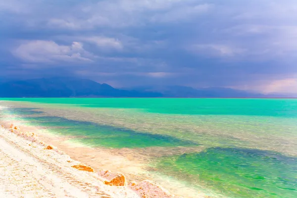 低い冬の雲は緑の海の水に反映されます 埋め立て堤防は海を通っています イスラエルだ 絵のように美しい死海 — ストック写真