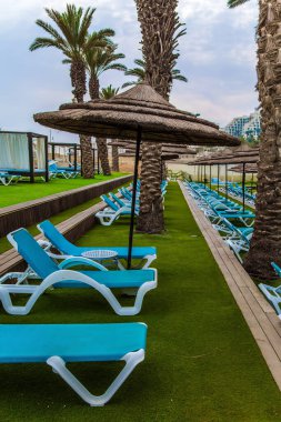 Meşhur şifalı Ölü Deniz. Şemsiyeli, palmiye ağaçlı ve güneşli bir sahil. Sisli bir kış sabahı. Ekolojik, plaj ve fotoğraf turizmi kavramı