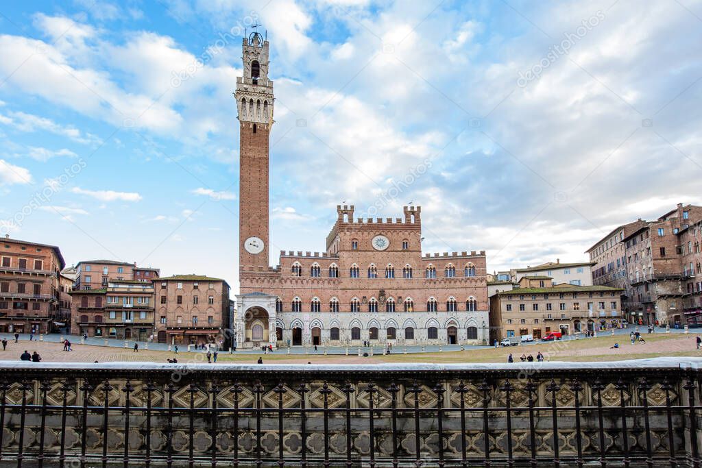 Winter trip to Tuscany. The old city center of Siena. The famous expansive Piazza del Campo is a shell-shaped square. Torre del Mangia - the tallest tower in Siena