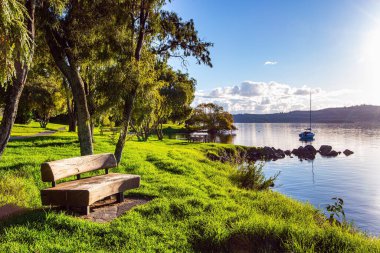 Rahat ahşap bir bank. Yeni Zelanda 'daki en büyük Taupo Gölü. Muhteşem göl turistler için popüler bir tatil beldesidir. Gölde sıcak bir akşam. Muhteşem gün batımı. 